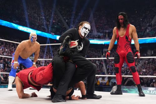 Professional wrestling Sting applies the Scorpion Deathlock to one of the Young Bucks while his sons watch.