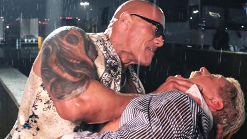 The Rock holds Cody Rhodes by the head in the rain.