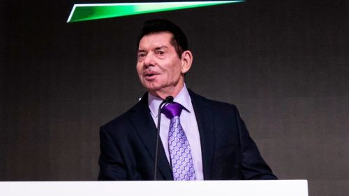 An older gentleman with dark hair wearing a suit stands at a podium with a microphone.