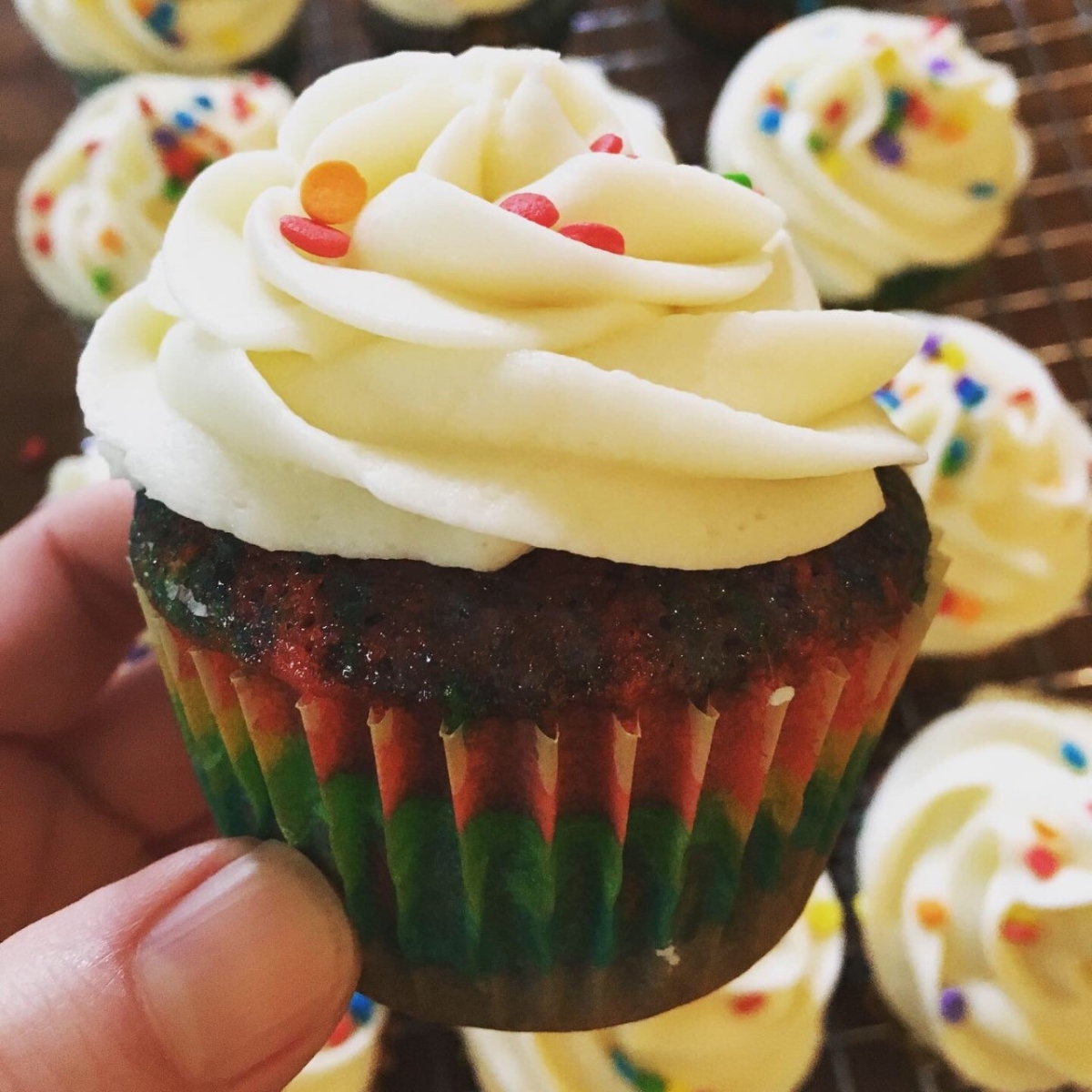 Rainbow cupcake with white vanilla frosting and some sprinkles on the top